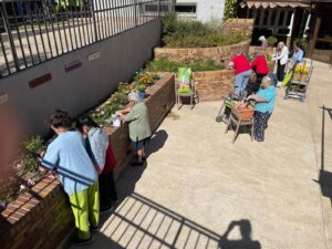 Residentes y Auxiliares cooperando a plantar las flores en espacio exterior